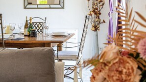 Un'area pranzo con un tavolo di legno apparecchiato per due persone, un vaso con fiori secchi e uno specchio appeso al muro.