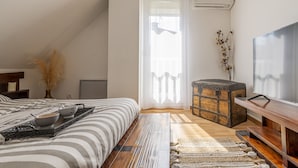 Una camera da letto con un letto, un baule di legno, una televisione e una finestra con tende.