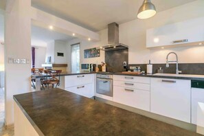 A modern kitchen with a central island, built-in oven, and stainless steel appliances.
