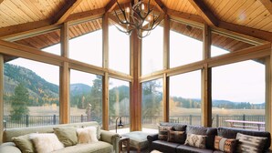 Ein geräumiges Zimmer mit großen Fenstern, einem Chandelier und Blick auf eine gebirgige Landschaft.