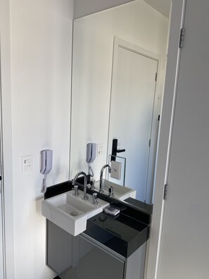 A modern bathroom with two sinks, a mirror, and a glass partition. - Akile Vergueiro (São Paulo)
