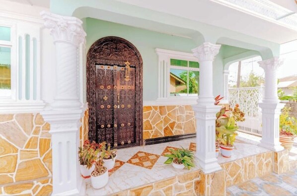 Stunning entrance with ornate carvings, white columns, and a geometric stone wall.
