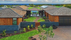 A modern residential complex with multiple houses, a central patio, and a view of the ocean. - Hale Kupanaha: Opulent New Villa + Pool/Spa/Views (Koloa)