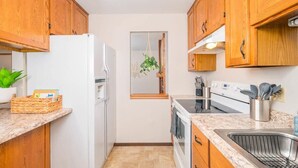 Una cocina compacta con gabinetes de madera, un refrigerador blanco, una estufa y un lavabo.