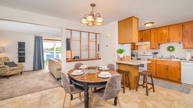 Una cocina moderna con armarios de madera, un comedor con una mesa redonda y una sala de estar con sofá y televisor.