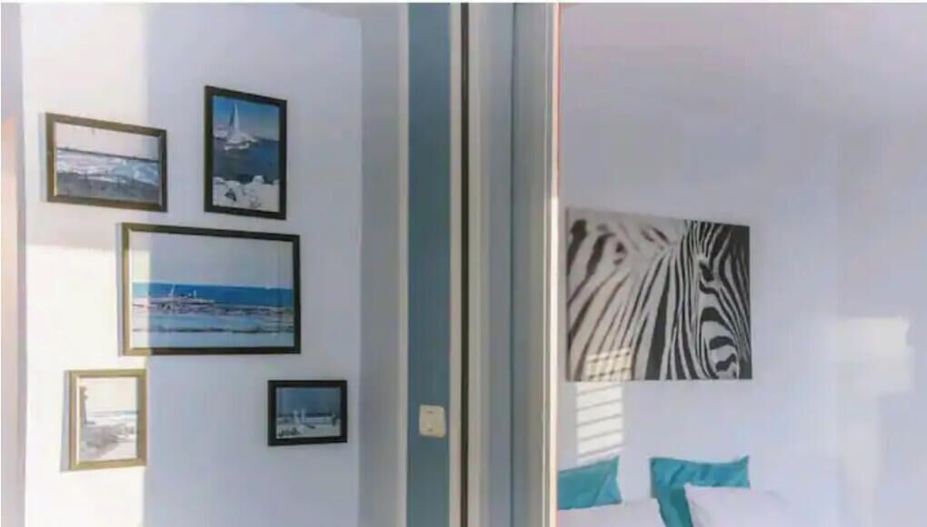 A room with a bed, a nightstand, and a wall with framed pictures.
