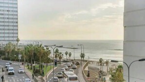 A busy urban street with a view of the sea, palm trees, and a pedestrian walkway. - Stunning Rooftop apartment on Hayarkon St (Tel Aviv-Yafo)