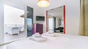 A hotel room with a large bed, a TV mounted on the wall, and a balcony with outdoor furniture. - Stunning Rooftop apartment on Hayarkon St (Tel Aviv-Yafo)