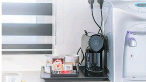A coffee machine with a drip tray, a coffee pod holder, and a water reservoir. - Stunning Rooftop apartment on Hayarkon St (Tel Aviv-Yafo)