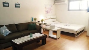 Un salon comprenant un canapé, une table basse, un lit et une petite table ornée d’objets décoratifs.