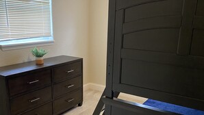 A bedroom with a dark wooden bed, a dresser, and a window with blinds. - Clearwater Home Away from Home (Clearwater)