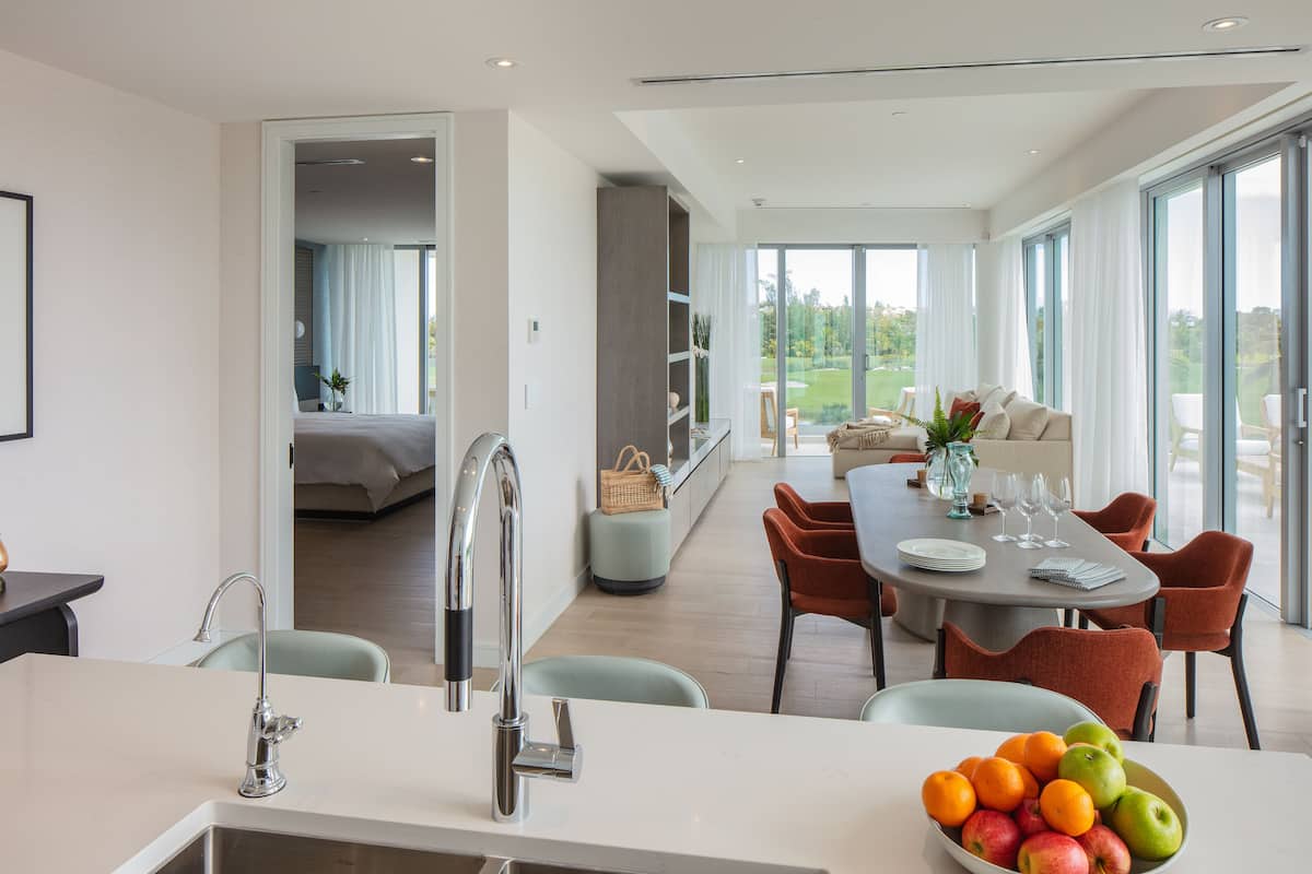 A modern kitchen with a sink, a dining area with a table and chairs, and a view of the outdoors.