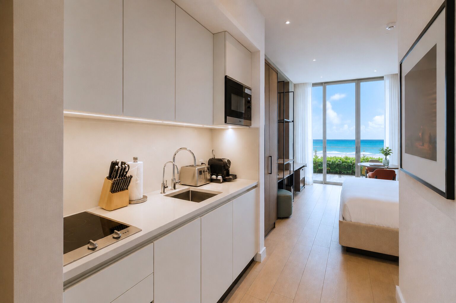 Eine moderne Küche mit Mikrowelle, Spüle und Toaster, die zu einem Balkon mit Meerblick führt.
