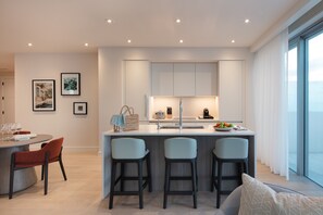 A modern kitchen with a central island, bar stools, and a dining area with a round table and chairs.