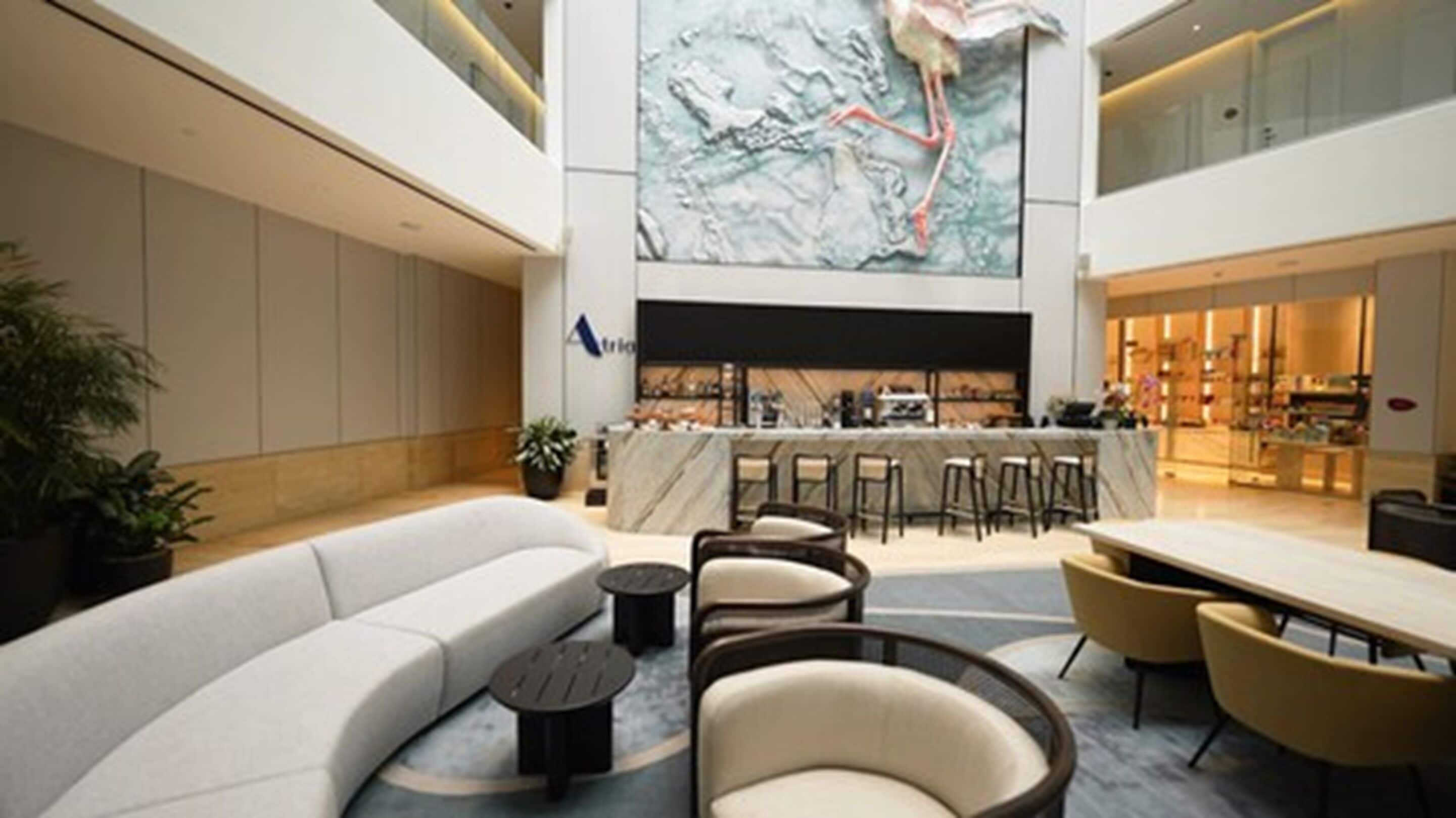 A spacious lobby with a large seating area, a bar, and a high ceiling with a mural.