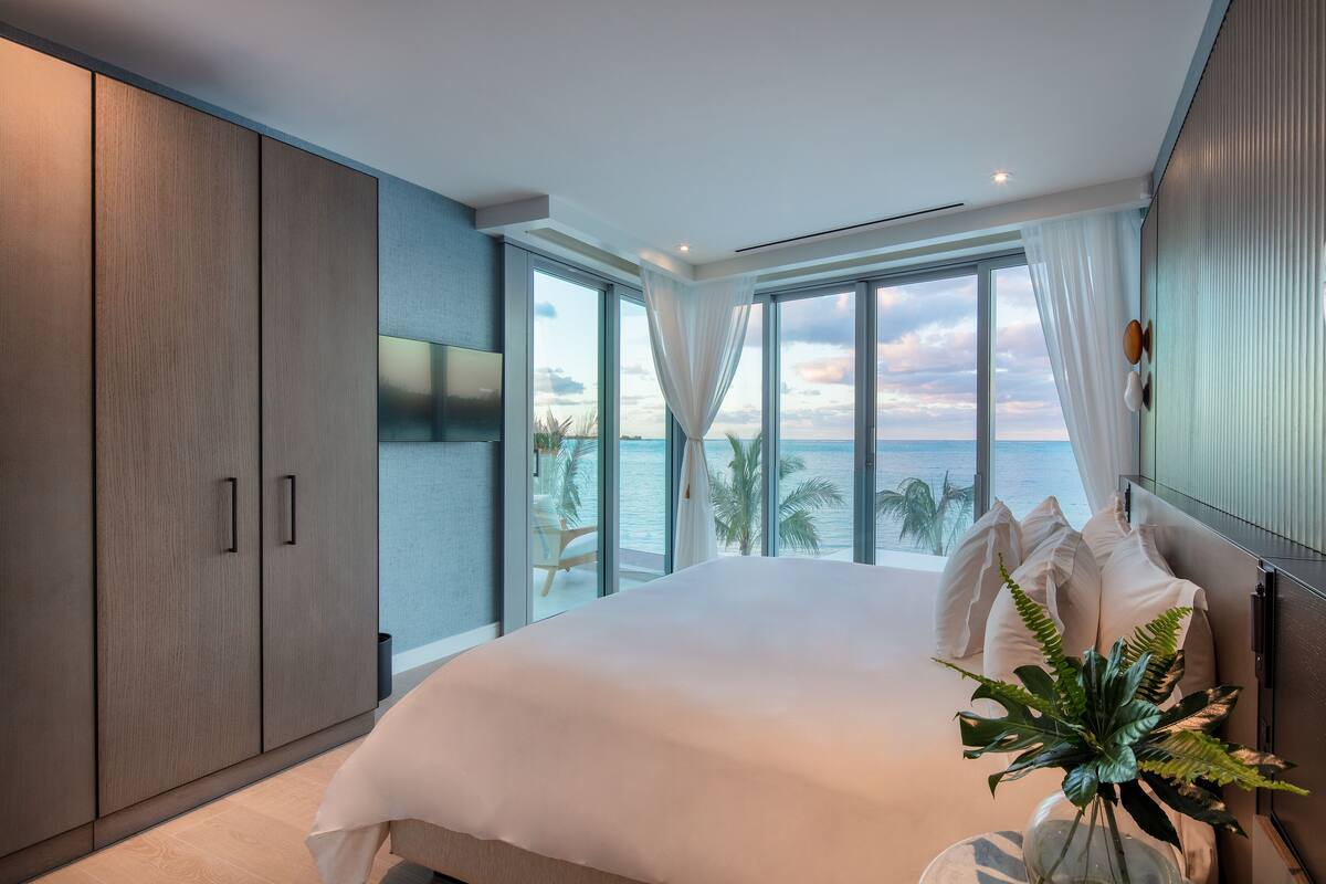 A bedroom with a large bed, a view of the ocean, and a sliding door closet.
