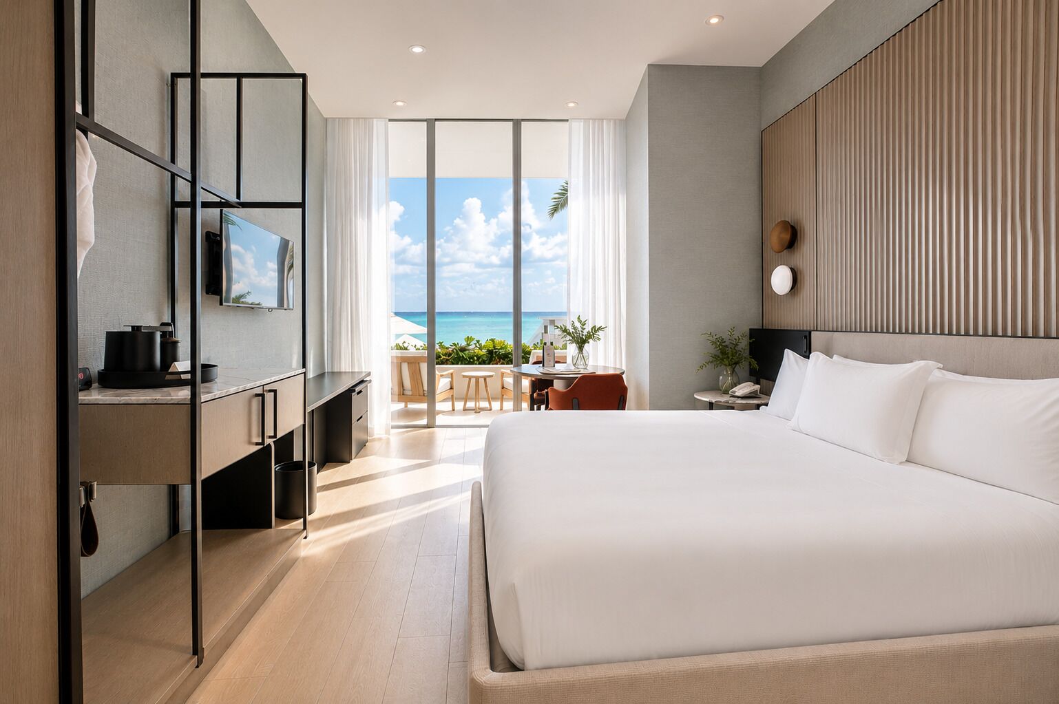 Habitación de hotel moderna con una cama grande, un escritorio con una silla, un televisor y vistas al océano.