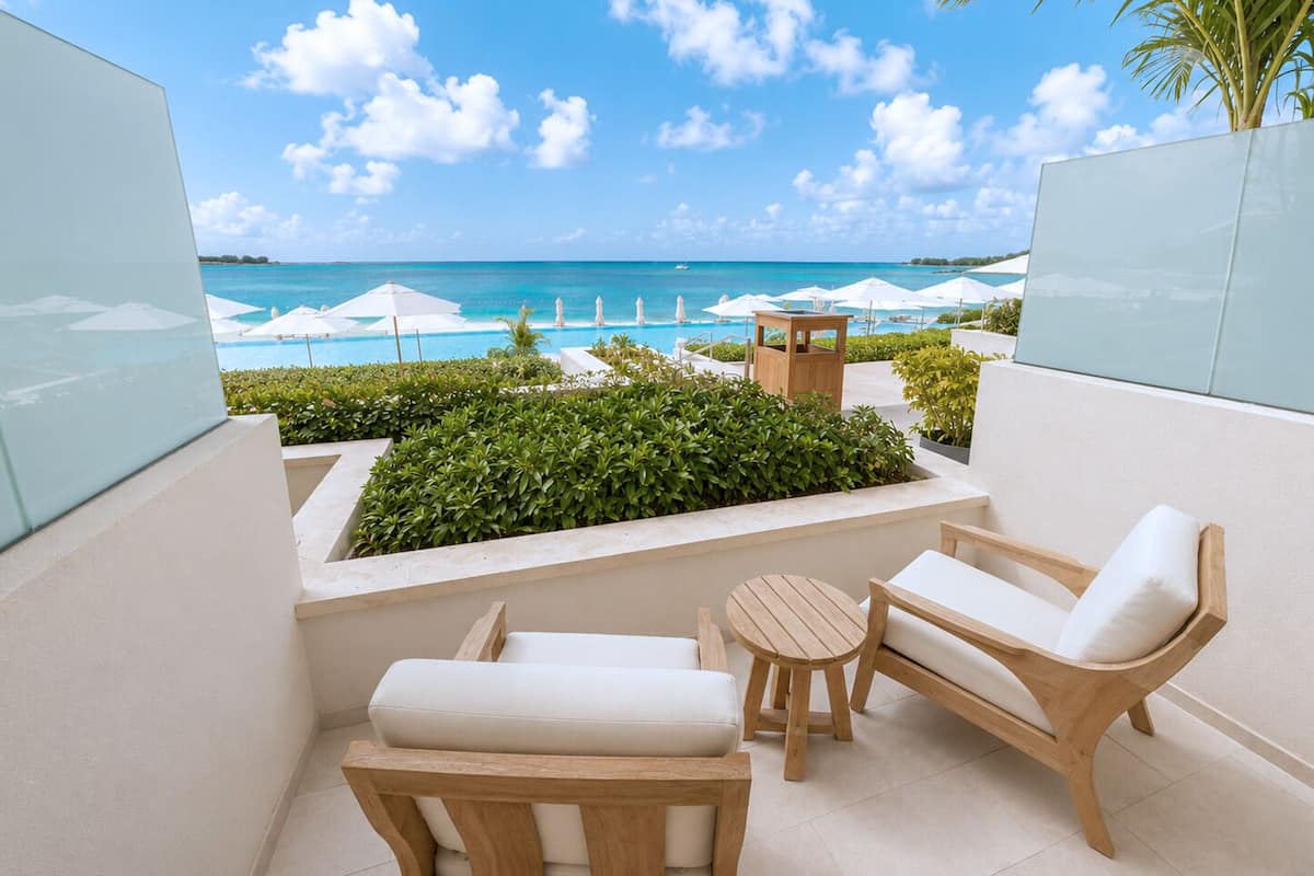 A balcony with a view of the ocean, wooden furniture, and a small table.