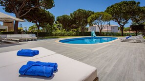 Un área de piscina con sillones de descanso, un tobogán y un edificio pequeño.