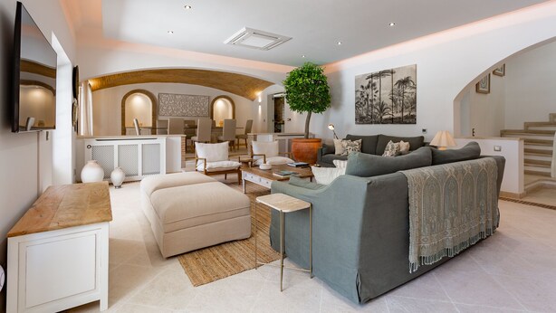 A modern living room with a sofa, coffee table, and a TV mounted on the wall. - Portuguese mansion close to marina, golf and beach. (Quarteira)
