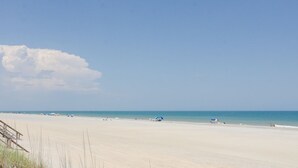 Una platja amb cel blau, sorra daurada i uns quants ombrel·les.