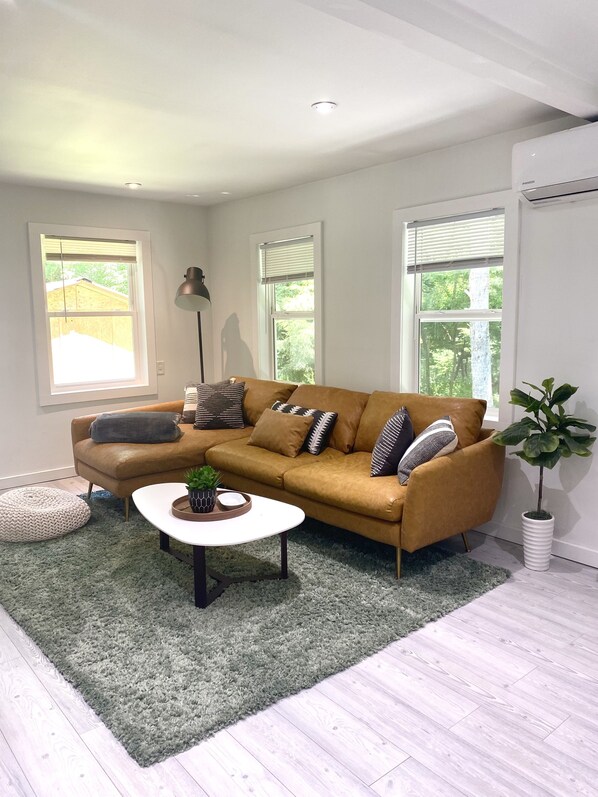 A modern living room with a brown leather sofa, a round coffee table, and a green rug.