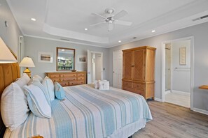 A bedroom with a bed, a wooden wardrobe, a ceiling fan, and a door leading to another room. - Lagoon-Front Retreat w/ Pool, Spa, Game Room & Private Dock Short Walk to Beach (Hilton Head Island)