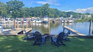 Un port de plaisance avec des bateaux amarrés, une zone herbeuse avec des fauteuils Adirondack et une jetée qui s’avance dans l’eau.