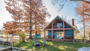 Une cabane dotée d’un balcon, d’une terrasse et d’un espace aménagé avec un foyer.