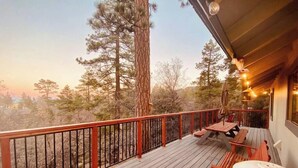 Eine Holzterrasse mit Geländer, Sitzgelegenheiten und Blick auf Bäume.