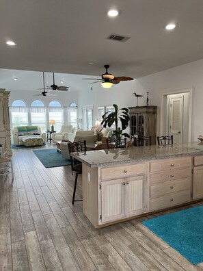 A spacious kitchen with a large island, wooden cabinets, and a ceiling fan. - Spacious beach home with a wrap around porch with beautiful views (Navarre)