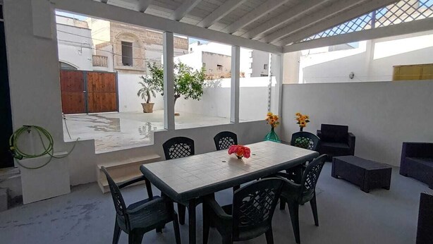 Ein offener Wohnbereich mit Esstisch und Stühlen, einer Couch und einem kleinen Balkon mit Blumentöpfen.