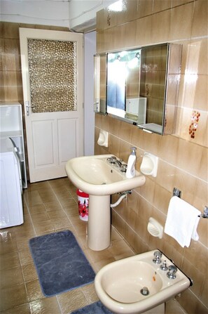 Een bad/douchecombinatie, een bidet, handdoeken