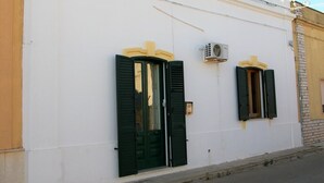 Ein Gebäude mit zwei Türen, jeweils mit grünen Fensterläden und einem kleinen Fenster darüber.