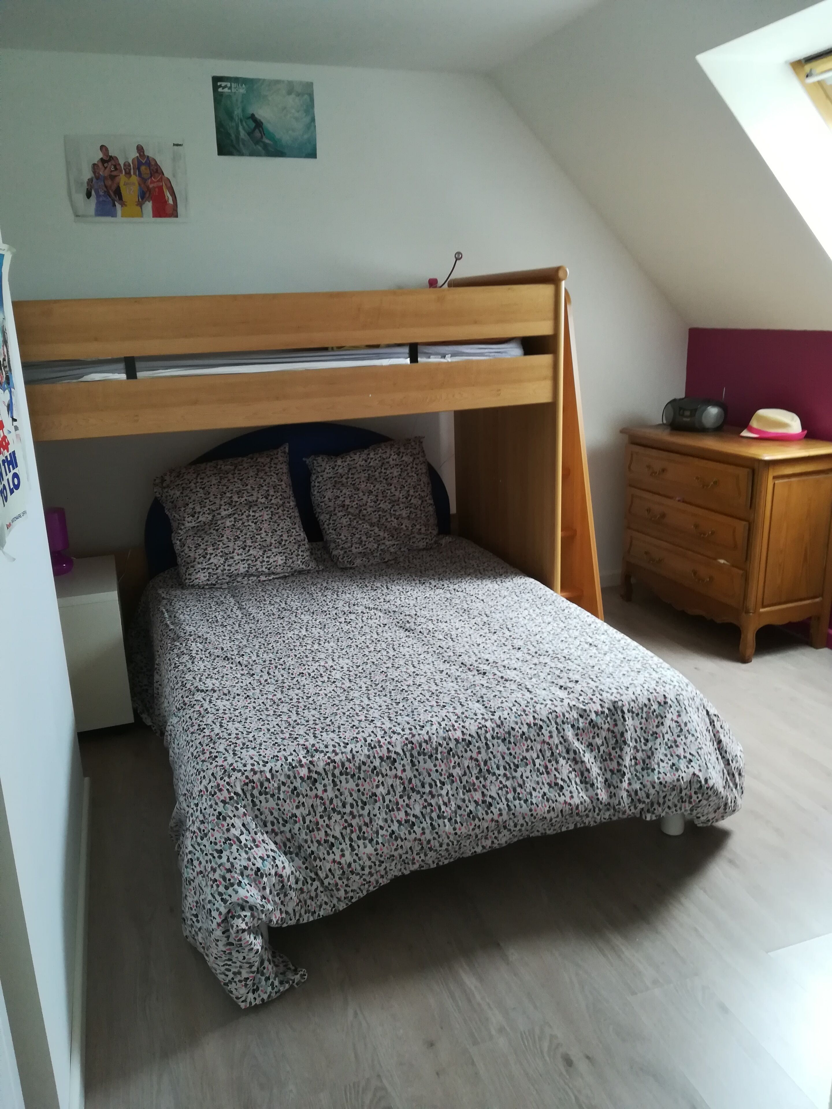 A bedroom with a bunk bed, a wooden dresser, a radio, and a painting on the wall.
