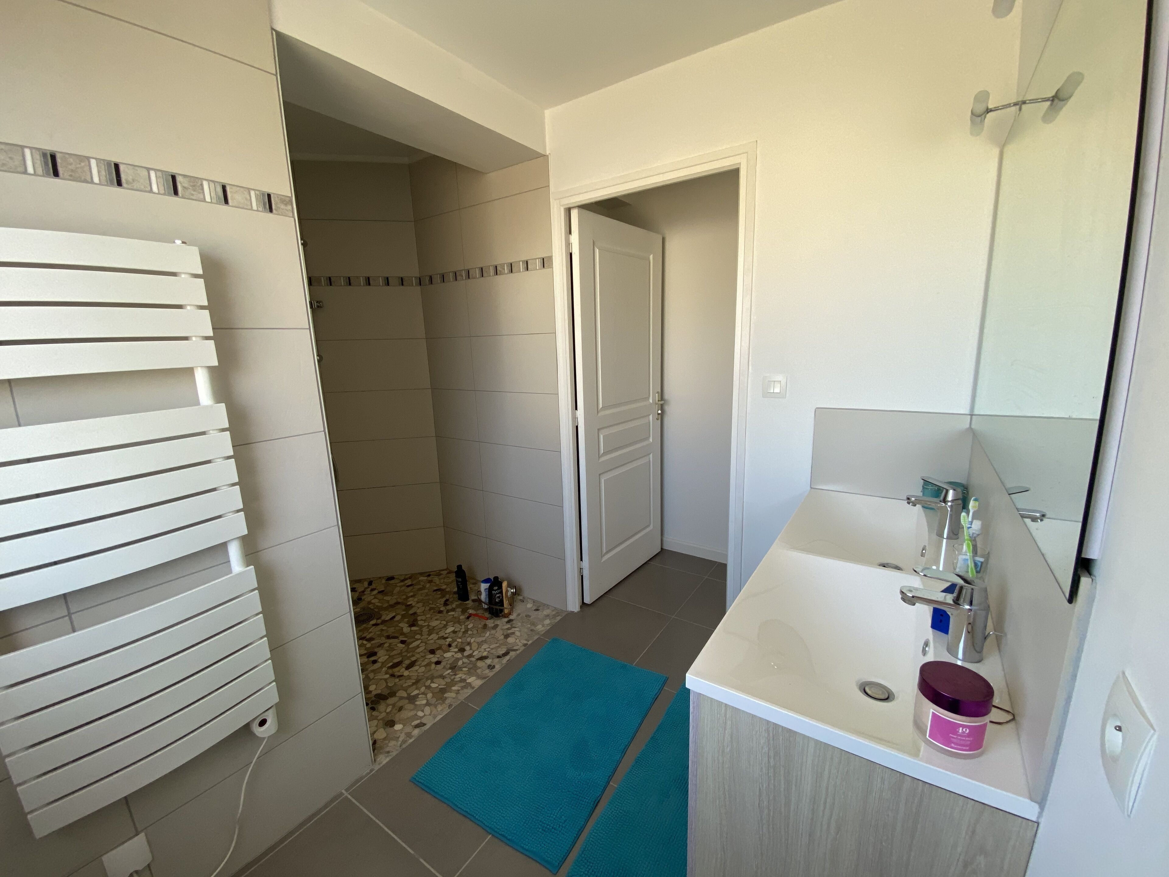 Une salle de bain avec une douche, un lavabo avec un miroir et un porte-serviettes.