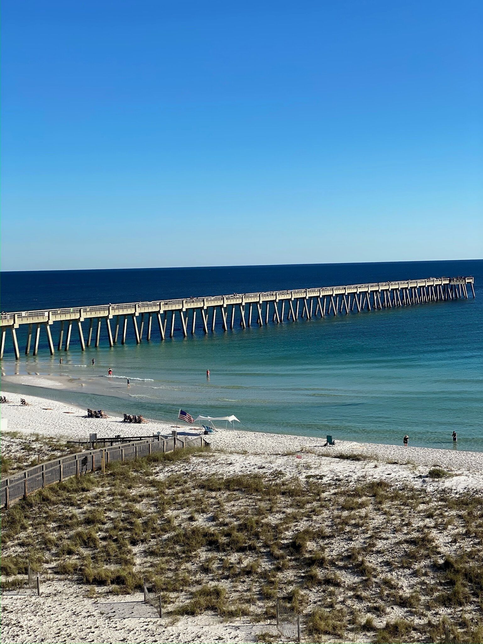 A pier extending into the ocean with a beach in the foreground.
