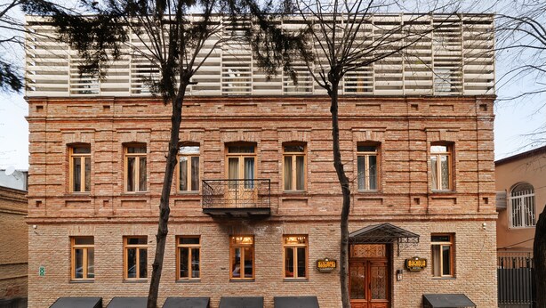 A brick building with multiple windows, a balcony, and a sign indicating it is a hotel.