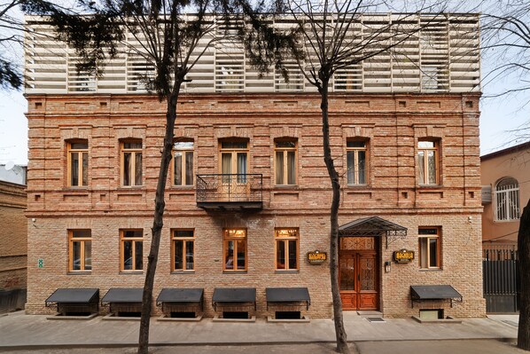 Un bâtiment en briques doté de nombreuses fenêtres, d’un balcon et d’une enseigne indiquant qu’il s’agit d’un hôtel.