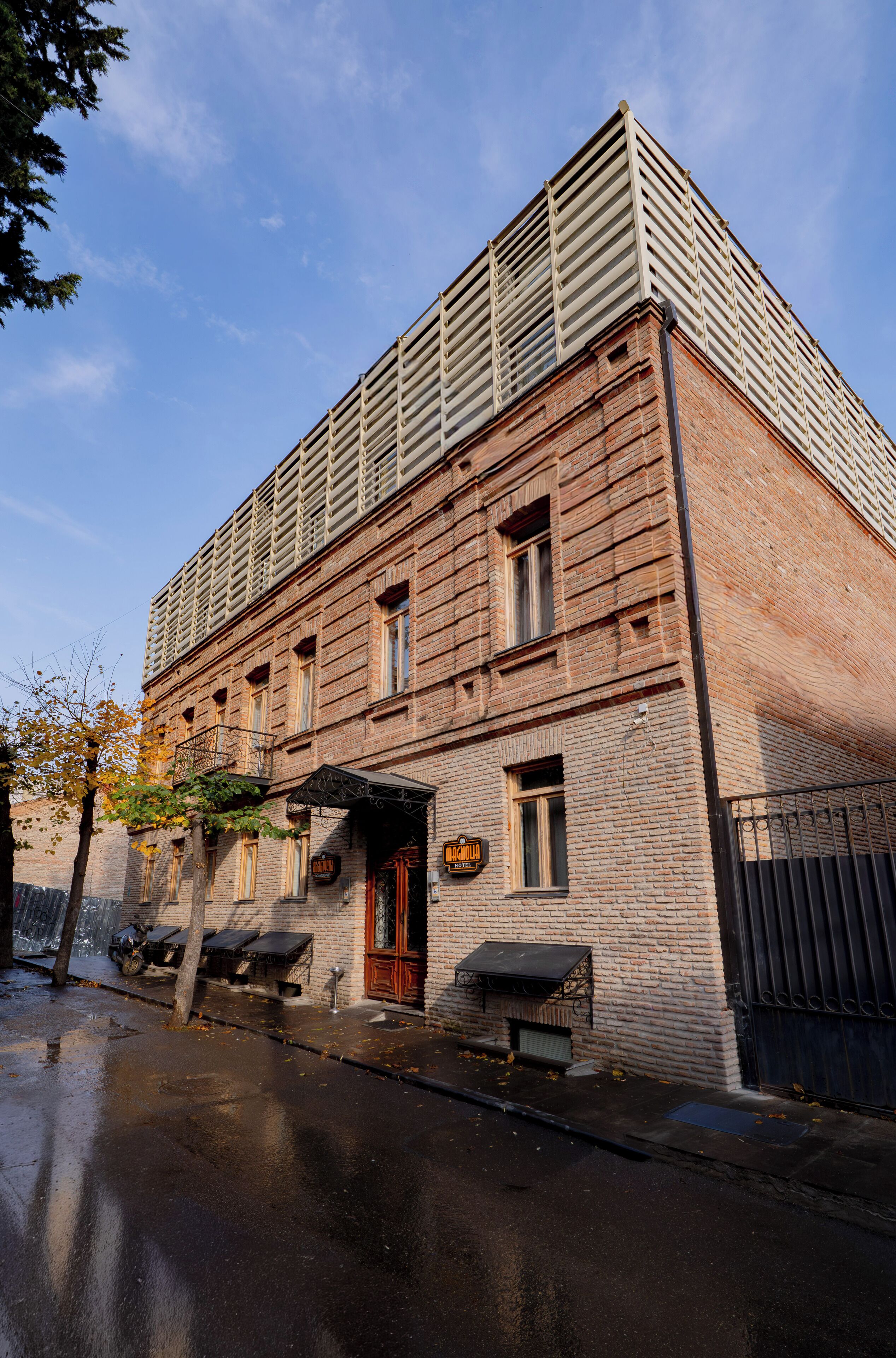 A historic building with a brick facade, a flat roof, and a small entrance with a door and window.