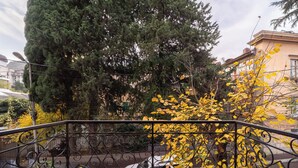A staircase with a metal railing, a parked car, and trees with yellow leaves in the background.