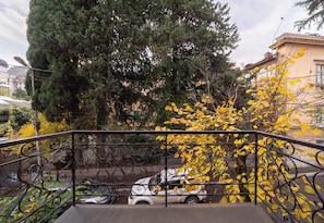 A staircase with a metal railing, a parked car, and trees with yellow leaves in the background.