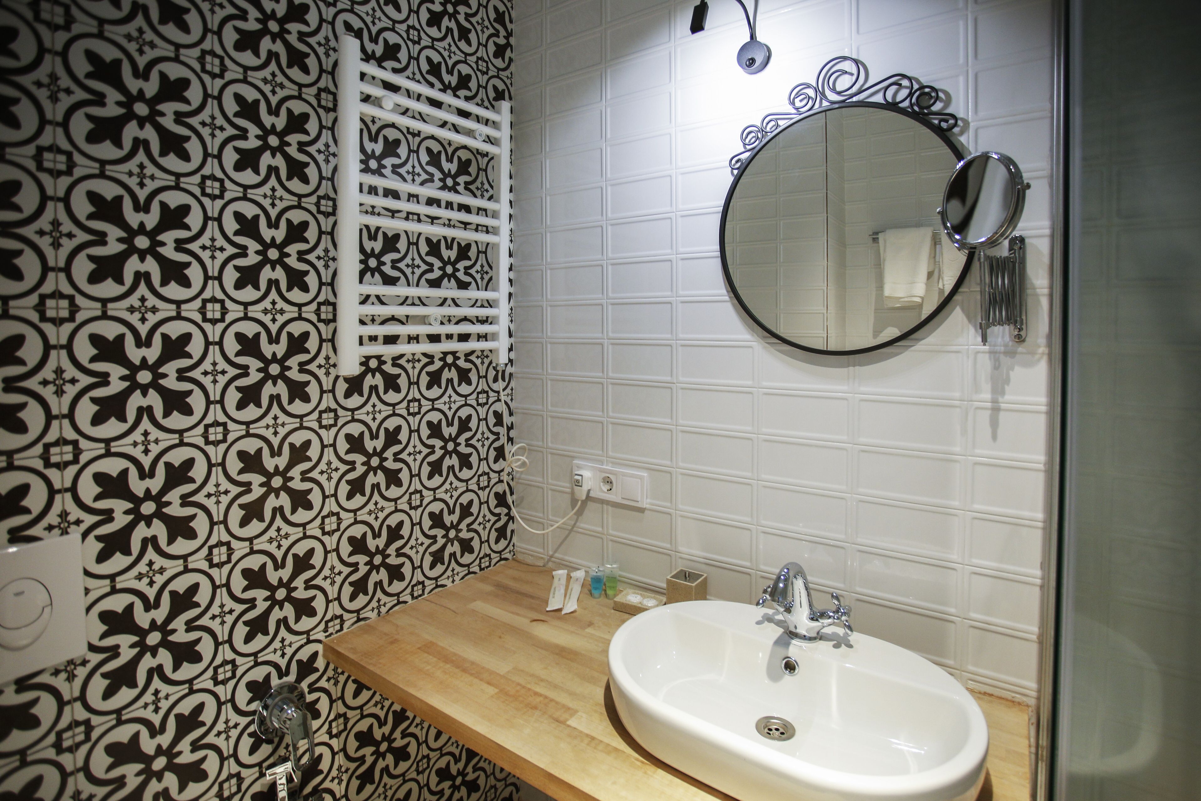 A bathroom with a white sink, a mirror, and patterned tiles.