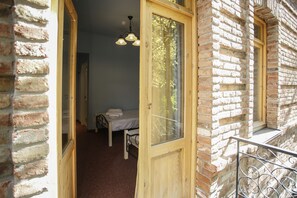 Une pièce avec un lit, une porte en bois et une fenêtre.