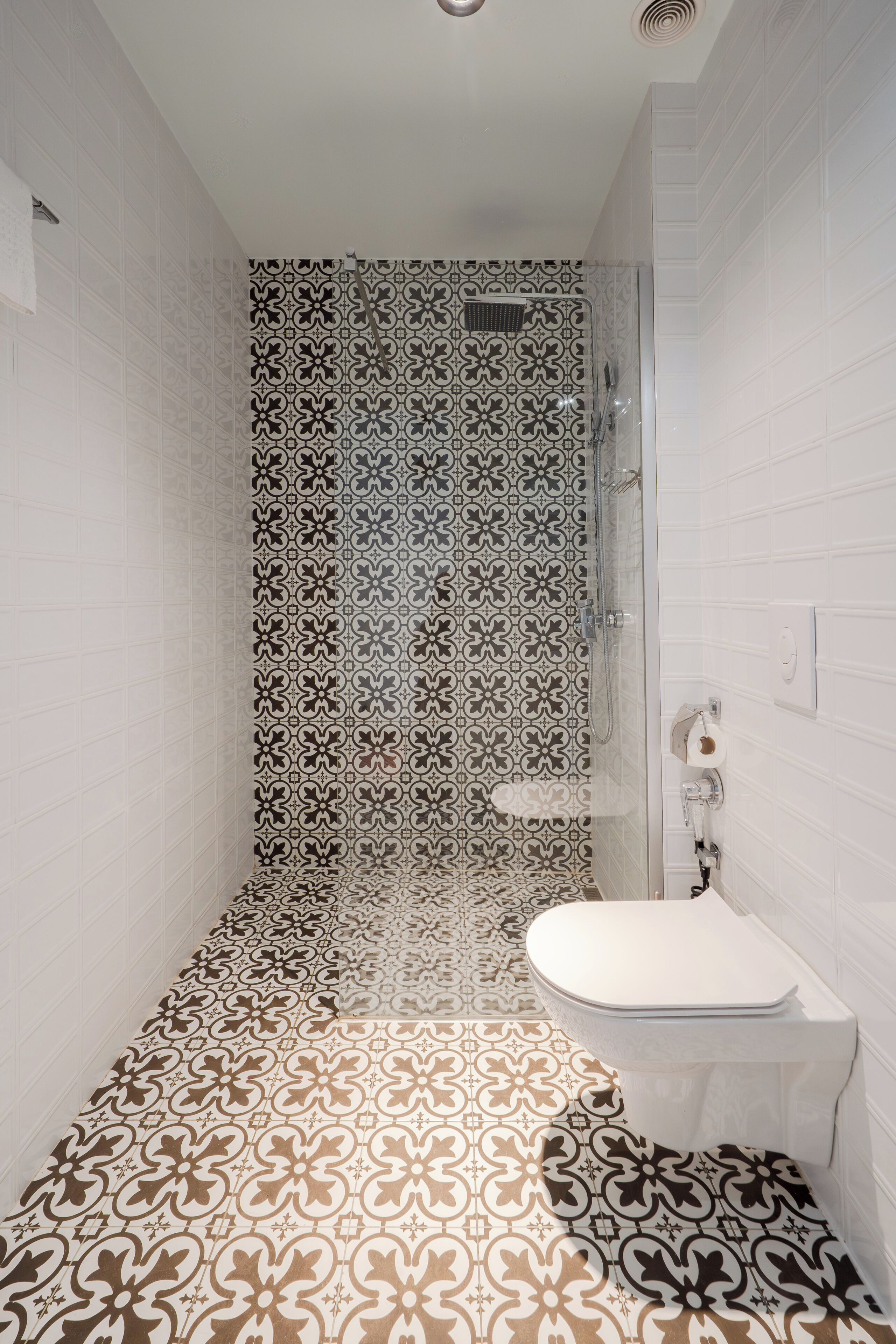 Un bany amb rajoles estampades, un vàter i un lavabo.