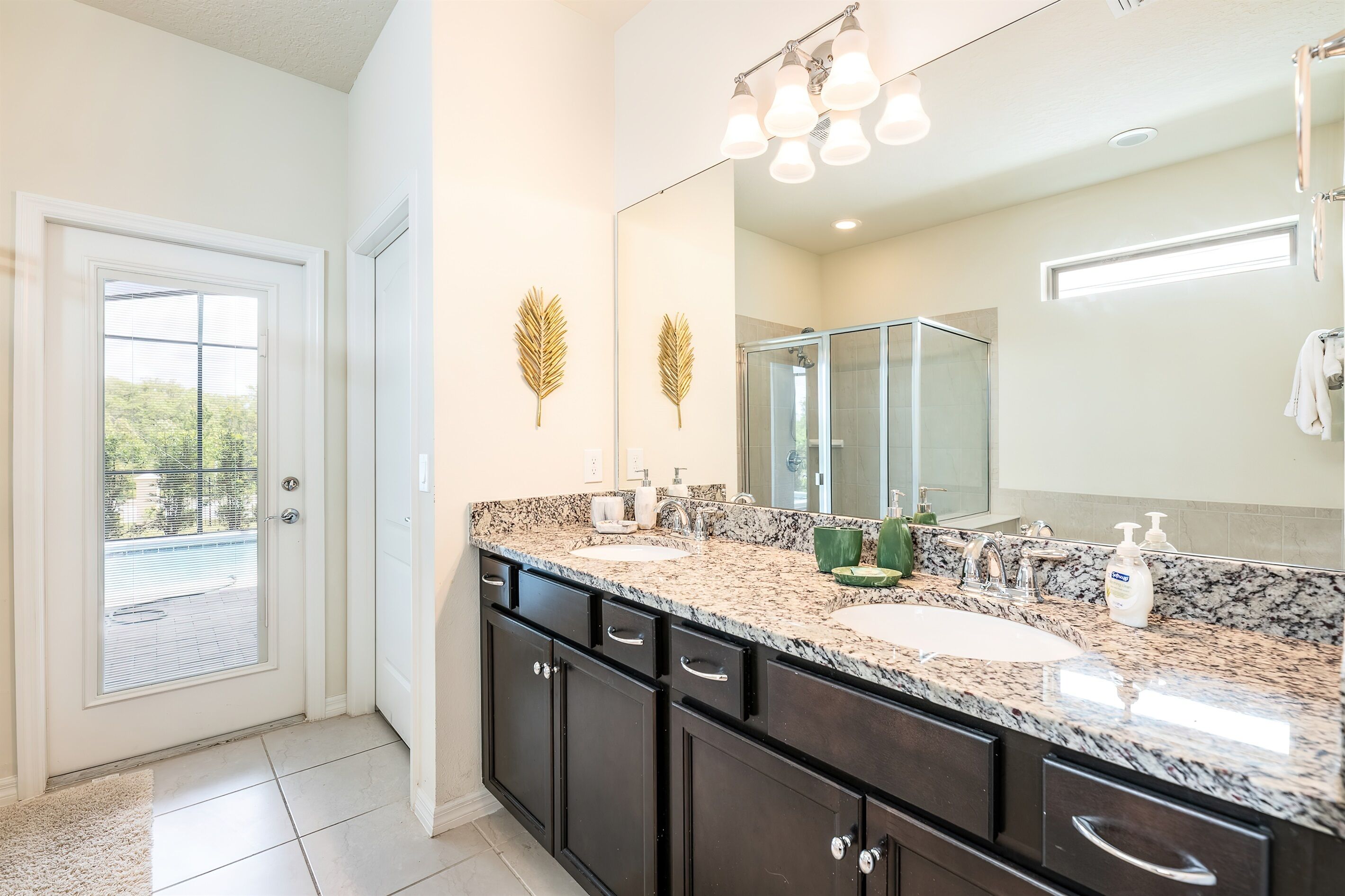 A bathroom with a large mirror, two sinks, and a shower.