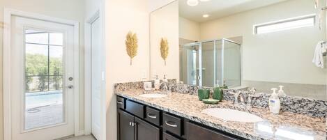 A bathroom with a large mirror, two sinks, and a shower.