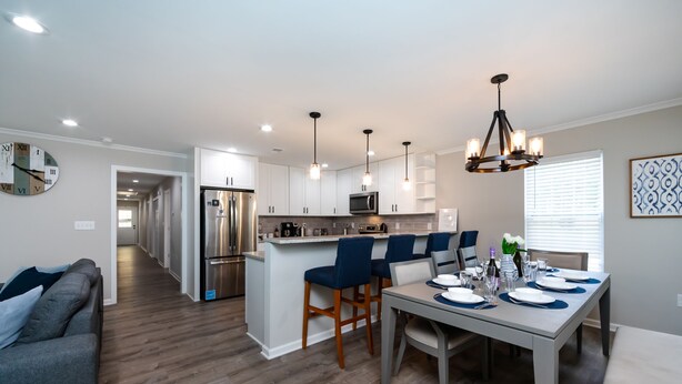 A modern kitchen with white cabinets, stainless steel appliances, and blue bar stools.