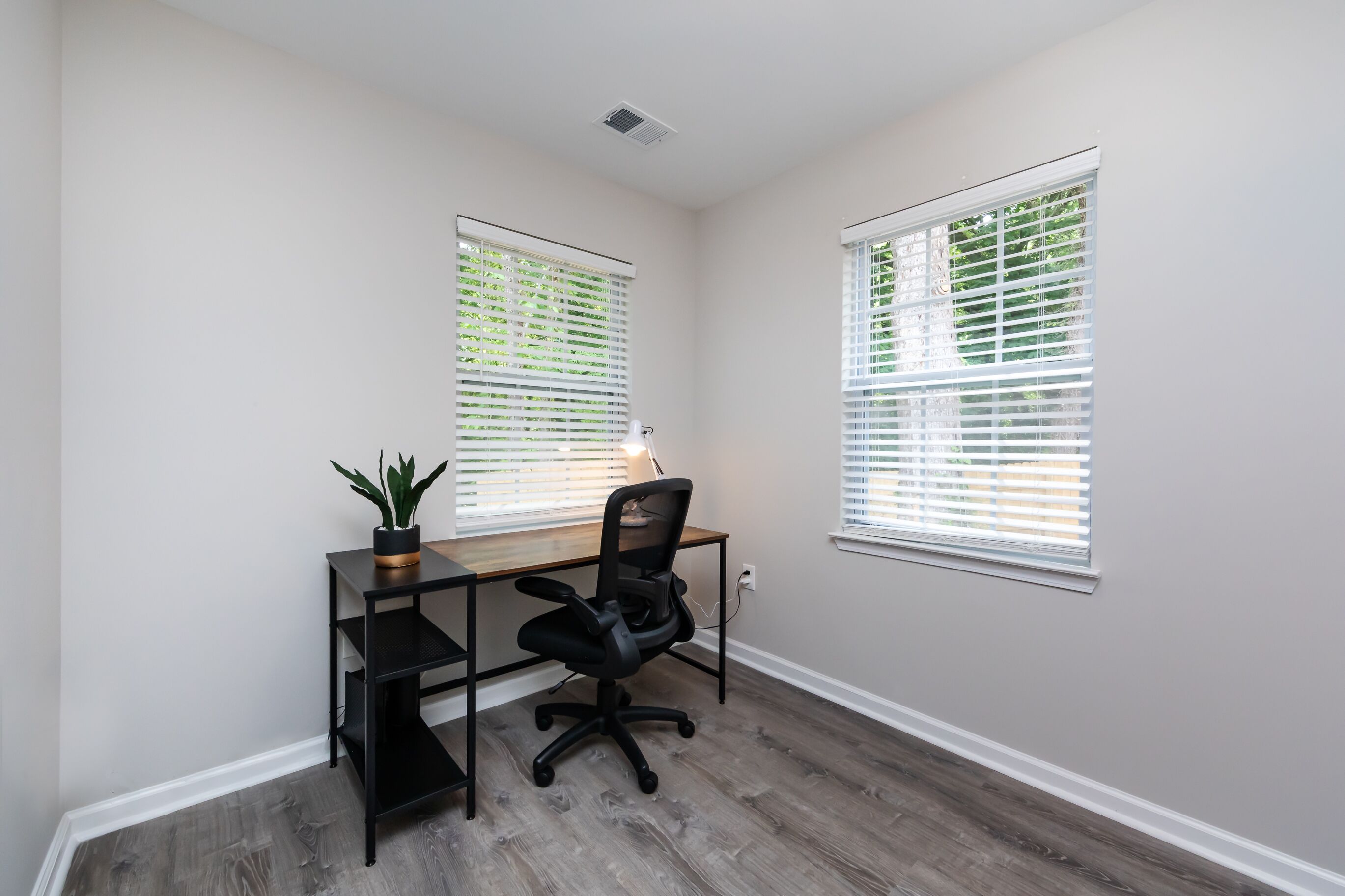 A small office space with a desk, chair, and a potted plant.