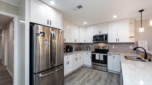 A modern kitchen with stainless steel appliances, white cabinetry, and a granite countertop.